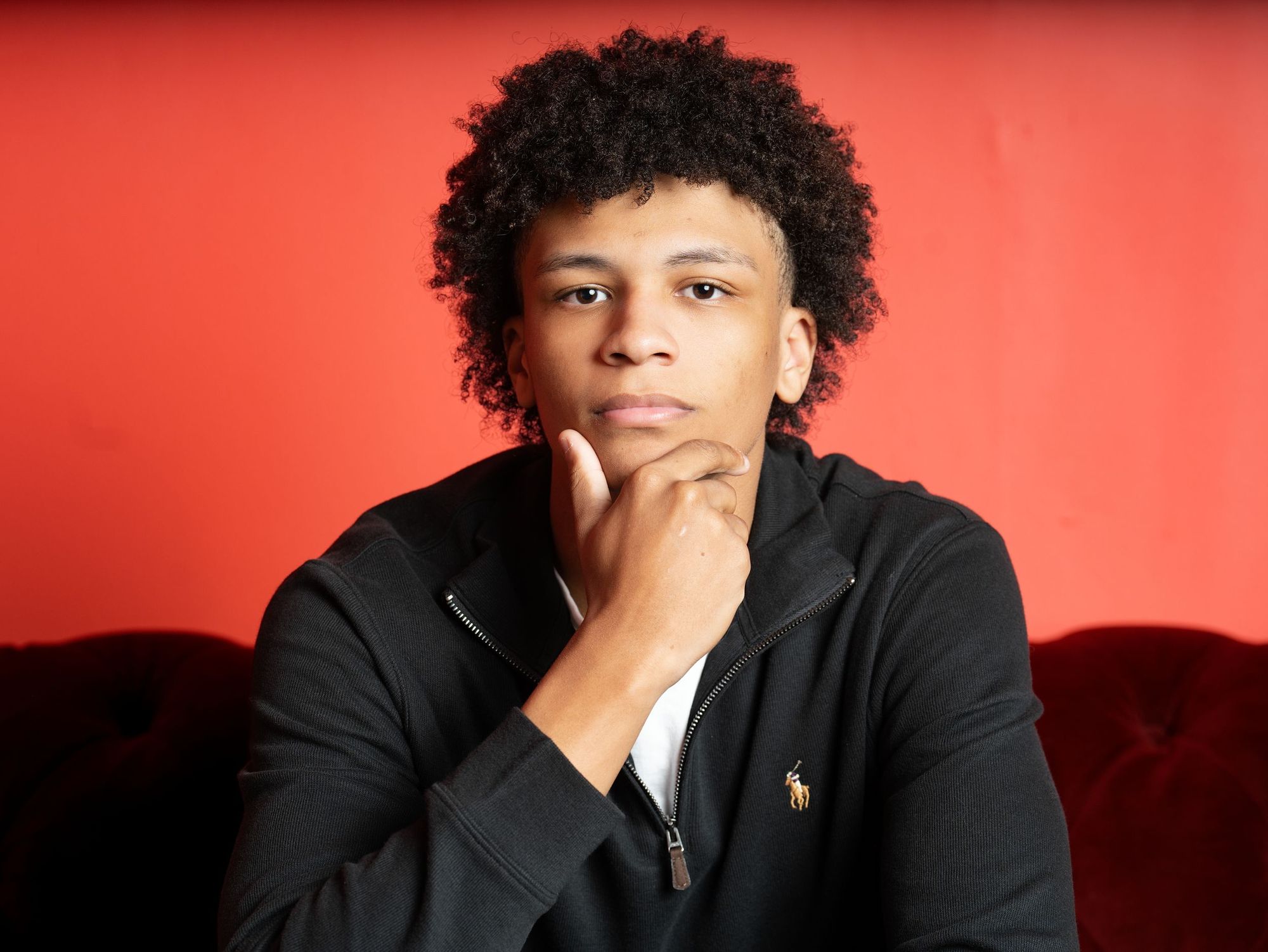 Young man posing against a red studio backdrop