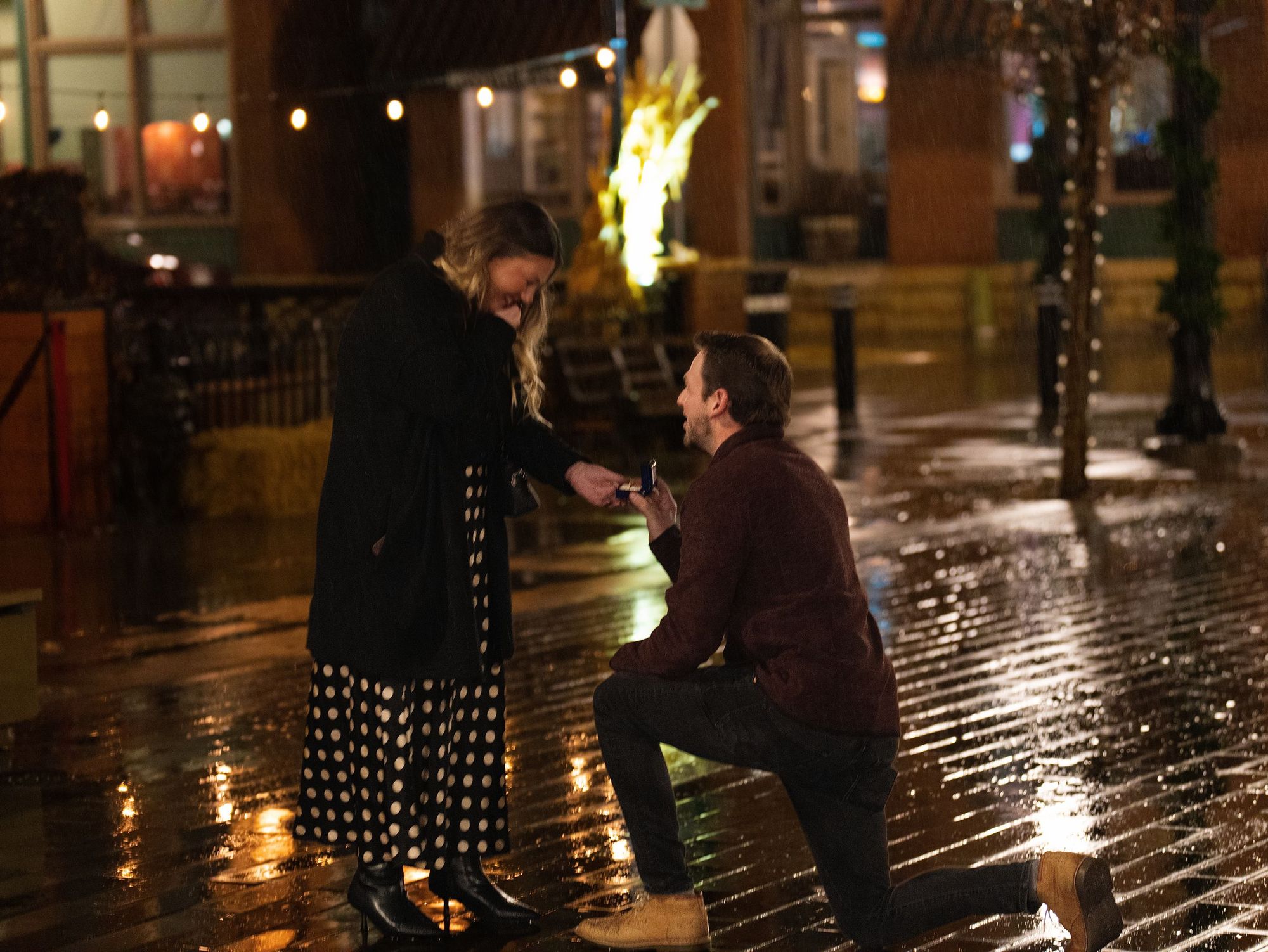 A proposal on a rain-wet street at night