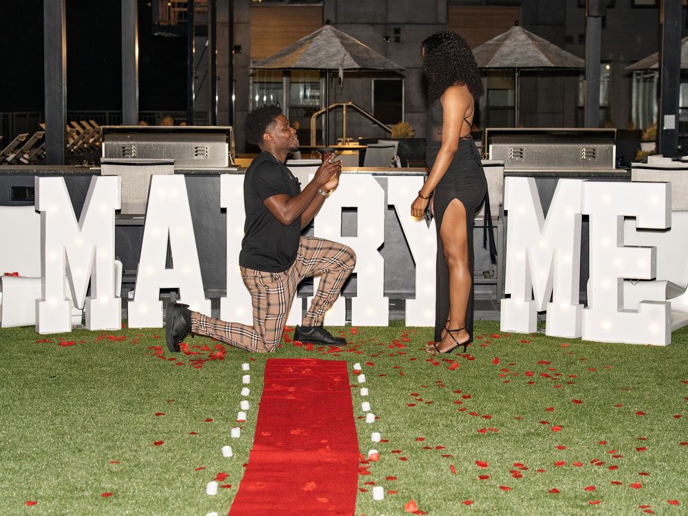 Proposal on a red carpet with MARRY ME letters at night